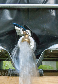 photo of a faucet spouting water from a rainwater collection  tank